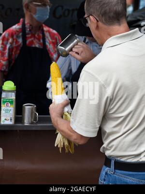 Un homme achète deux épis de maïs torréfié sur le rafle d'un stand de restauration lors d'un festival en plein air à Santa Fe, Nouveau-Mexique. Banque D'Images