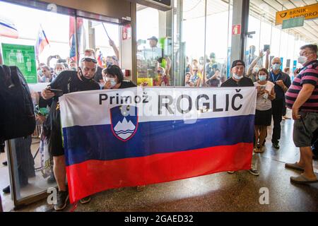 Zgornji Brnik, Slovénie. 30 juillet 2021. Les fans ont vu porter un grand drapeau slovène tout en attendant le procès individuel en vélo de route slovène, Primoz Rogall, médaillé d'or olympique, pour les accueillir à son arrivée à l'aéroport de Ljubljana. (Photo de Luka Dakskobler/SOPA Images/Sipa USA) crédit: SIPA USA/Alay Live News Banque D'Images