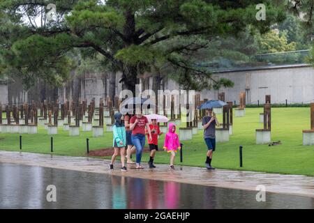 Oklahoma City, Oklahoma - visiteurs au monument commémoratif national d'Oklahoma City pendant une tempête de pluie. Le Mémorial marque le bombardement terroriste domestique de 1995 Banque D'Images