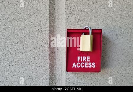 Boîte d'accès au feu rouge avec cadenas sur un mur texturé Uni avec espace de copie. Banque D'Images