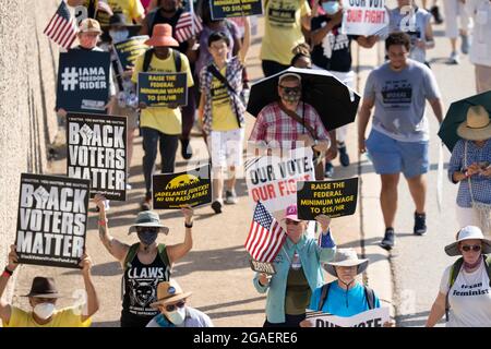 Austin, Texas, États-Unis, 30 juillet 2021 : les groupes de droits de vote défilent le long d'une route de desserte autoroutière vers le capitole du Texas depuis le nord d'Austin le troisième jour d'un voyage de 30 miles protestant contre les efforts des Républicains pour supprimer les votes dans tout le pays et au Texas. Des changements de marcheurs se font échanger dans un effort pour lutter contre la chaleur oppressive du Texas. Crédit : Bob Daemmrich/Alay Live News Banque D'Images