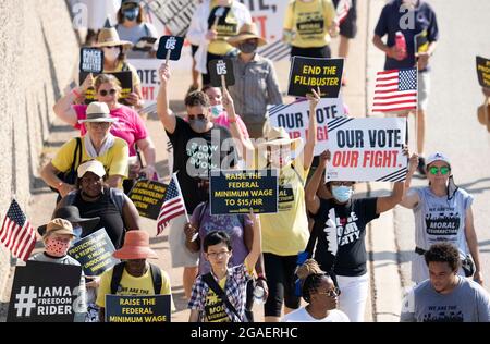 Austin, Texas, États-Unis, 30 juillet 2021 : les groupes de droits de vote défilent le long d'une route de desserte autoroutière vers le capitole du Texas depuis le nord d'Austin le troisième jour d'un voyage de 30 miles protestant contre les efforts des Républicains pour supprimer les votes dans tout le pays et au Texas. Des changements de marcheurs se font échanger dans un effort pour lutter contre la chaleur oppressive du Texas. Crédit : Bob Daemmrich/Alay Live News Banque D'Images