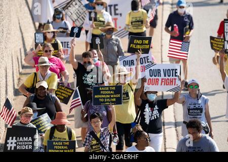Austin, Texas, États-Unis, 30 juillet 2021 : les groupes de droits de vote défilent le long d'une route de desserte autoroutière vers le capitole du Texas depuis le nord d'Austin le troisième jour d'un voyage de 30 miles protestant contre les efforts des Républicains pour supprimer les votes dans tout le pays et au Texas. Des changements de marcheurs se font échanger dans un effort pour lutter contre la chaleur oppressive du Texas. Crédit : Bob Daemmrich/Alay Live News Banque D'Images