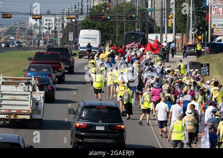 Austin, Texas, États-Unis, 30 juillet 2021 : les groupes de droits de vote défilent le long d'une route de desserte autoroutière vers le capitole du Texas depuis le nord d'Austin le troisième jour d'un voyage de 30 miles protestant contre les efforts des Républicains pour supprimer les votes dans tout le pays et au Texas. Des changements de marcheurs se font échanger dans un effort pour lutter contre la chaleur oppressive du Texas. Crédit : Bob Daemmrich/Alay Live News Banque D'Images