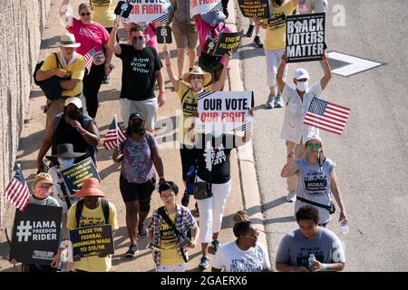 Austin, Texas, États-Unis, 30 juillet 2021 : les groupes de droits de vote défilent le long d'une route de desserte autoroutière vers le capitole du Texas depuis le nord d'Austin le troisième jour d'un voyage de 30 miles protestant contre les efforts des Républicains pour supprimer les votes dans tout le pays et au Texas. Des changements de marcheurs se font échanger dans un effort pour lutter contre la chaleur oppressive du Texas. Crédit : Bob Daemmrich/Alay Live News Banque D'Images