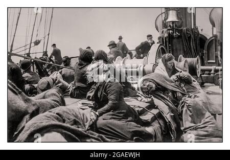 Archive 1900s Travel image Ocean Liner People passagers sur le pont en 'classe steerage' sur le pont du paquebot 1900's bain News Service. La direction est le pont inférieur d'un navire, où la cargaison est entreposée au-dessus de la cale fermée. À la fin du 19e siècle et au début du 20e siècle, les ponts de steerage des navires à vapeur étaient utilisés pour offrir le coût le plus bas et la classe de voyage la plus basse, souvent pour les immigrants européens et chinois en Amérique du Nord. Avec une intimité et une sécurité limitées, des conditions sanitaires inadéquates et une nourriture pauvre, Steerage a souvent été décrié comme inhumain, et a finalement été remplacé sur les paquebots de mer par des cabines de troisième classe. Banque D'Images