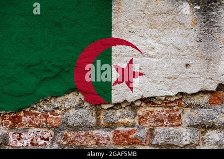 Concept graphique avec un drapeau d'Algérie peint sur un mur de briques endommagé. Banque D'Images