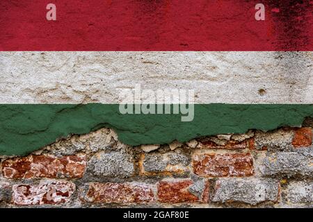 Concept graphique avec un drapeau de Hongrie peint sur un mur de brique endommagé. Banque D'Images