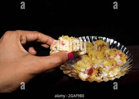 Une femme mangeant un savoureux aliment indien, le Bhelpuri populaire en-cas indien Banque D'Images