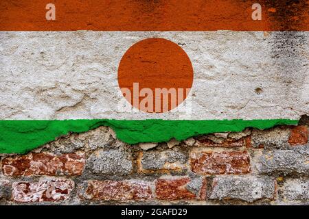 Concept graphique avec un drapeau du Niger peint sur un mur de briques endommagé. Banque D'Images