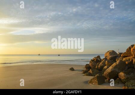 Couleur pastel cirrostratus nuageux plage tropicale lever de soleil paysage marin. Front de mer à l'aube avec un affleurement rocheux. Huay Yang, Thaïlande. Banque D'Images