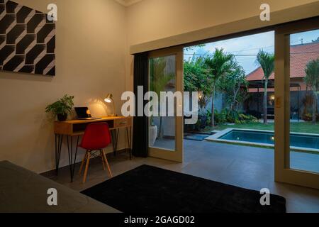 Décoration intérieure d'une chambre luxueuse et moderne, villa avec piscine, vue sur la piscine, jardin vert, transat ou transat sur la terrasse de la piscine, coussin bleu Banque D'Images