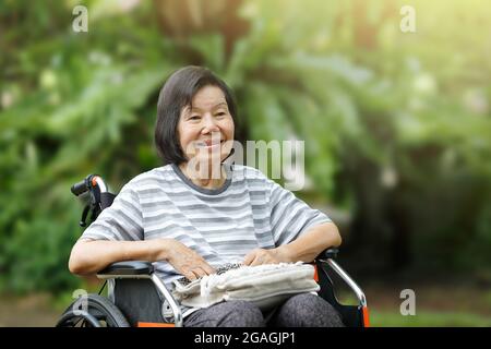 femme âgée souriante, assise en fauteuil roulant Banque D'Images