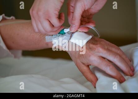 30 juillet 2021, Hessen, Groß-Gerau: Aylin Yalcin, un agent de santé et de soins infirmiers, s'occupe du patient Johanna Eleonora Sillinger de Worfelden, qui avait été opéré pour une main cassée, dans une salle de l'hôpital de district de Groß-Gerau. La deuxième vague de la pandémie de Corona a coûté beaucoup d'argent à la clinique du district de Groß-Gerau. De nombreux infirmiers étaient tombés malades avec Covid-19 ou ont dû aller en quarantaine. Les travailleurs temporaires ont dû combler cette lacune - et ils sont coûteux. (À dpa 'coûteux travail temporaire en soins infirmiers à l'hôpital - une conséquence de la pression des coûts') photo: Arne Dedert/dpa Banque D'Images