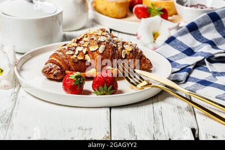 Gros plan sur des croissants appétissants et des crêpes au fromage cottage avec des fraises fraîches sur un fond rustique en bois. Petit déjeuner délicieux et sain. SWE Banque D'Images