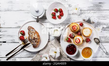 Bannière alimentaire. Croissants croustillants appétissants et crêpes au fromage cottage avec fraises fraîches et confiture de baies sucrées. Petit déjeuner délicieux et sain. SW Banque D'Images