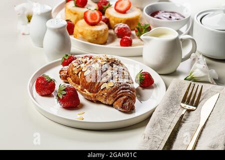 Petit déjeuner délicieux et sain. Croissants croustillants et crêpes au fromage cottage avec fraises fraîches et confiture de baies sucrées. Appétissant des aliments sucrés. Ouh Banque D'Images