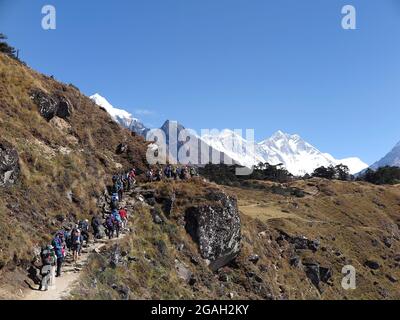 Les randonneurs se rendent sur la piste du bazar Namche avec vue sur le Mont Taboche (partiel) enneigé, Everest et Lhotse en arrière-plan Banque D'Images