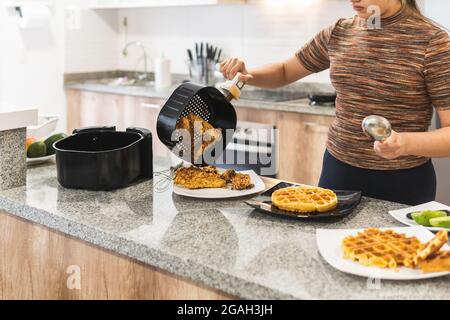 femme servant du poulet frit avec des gaufres à l'air fryer Banque D'Images