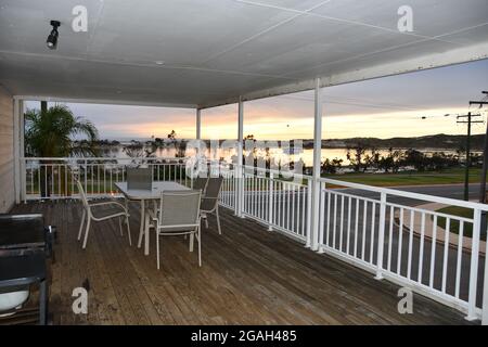 table à manger et chaises sur un balcon en bois donnant sur la rivière au coucher du soleil Banque D'Images