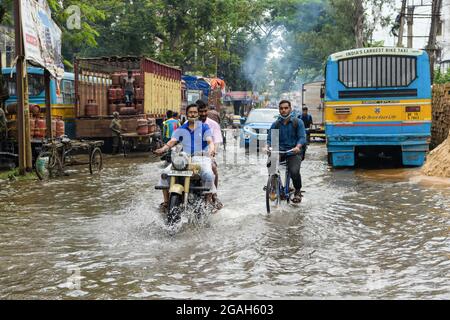 Kolkata, Inde. 30 juillet 2021. Les gens qui traversent une route engortée par l'eau au lendemain. Kolkata a reçu la plus grosse baisse de la saison causée par un système de basse pression au-dessus du Bangladesh et du Bengale occidental. Crédit : SOPA Images Limited/Alamy Live News Banque D'Images