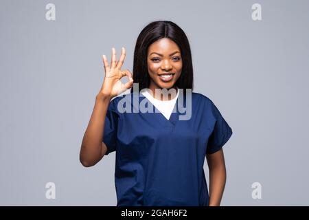 Afro américain chirurgien médecin tenant la planchette à pince femme sur isolé sur fond blanc faisant signe ok avec les doigts, excellent symbole Banque D'Images