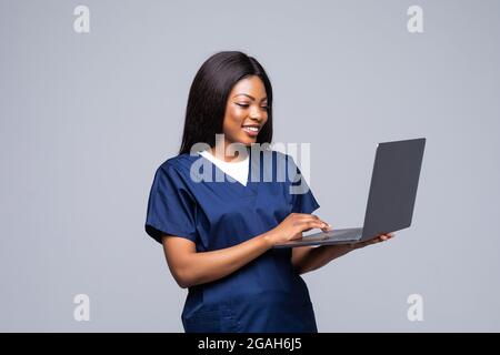 Femme infirmière ou médecin afro-américaine portant une forme médicale tenant un ordinateur portable isolé sur fond blanc Banque D'Images