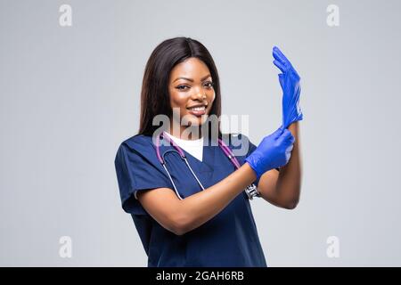 Infirmière africaine ou médecin femme portant un masque médical portant des gants jetables isolés sur fond blanc Banque D'Images