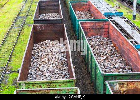 Industrie lourde - le charbon, le métal, le tuyau en fer carré est transporté dans les wagons de fret ferroviaire de la cour de train Banque D'Images