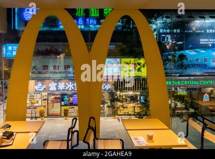 Une vue sur les restaurants et les centres de spa avec des enseignes au néon dans la nuit à travers la fenêtre avec "M" du restaurant McDonald's, Tsim Sha Tsui, Hong Kong, Chine Banque D'Images