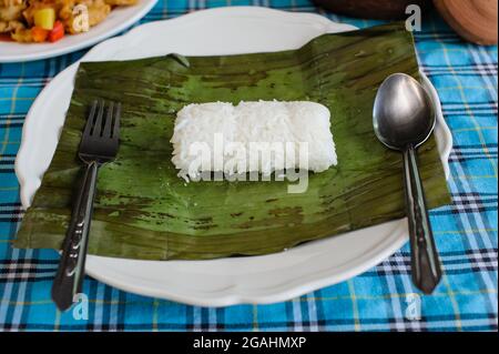 riz cuit à la vapeur avec une cuillère à feuille de banane et folk sur un plat Banque D'Images