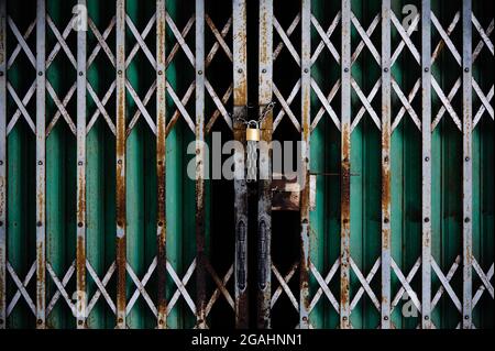 Porte en acier avec des barres qui se verrouillent avec une petite chaîne en acier et une serrure en or Banque D'Images