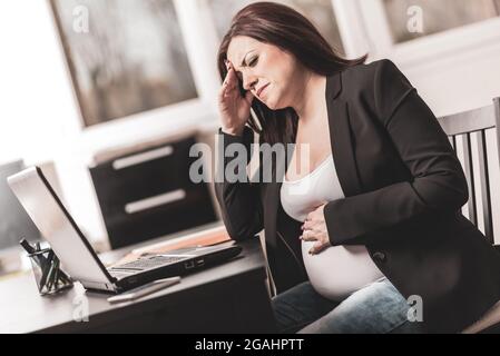Femme enceinte souffrant de maux de tête au bureau Banque D'Images