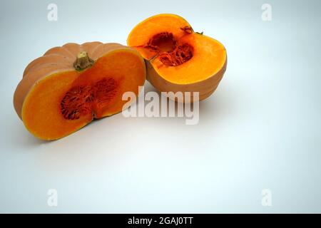 Une courge musquée ou une citrouille coupée en deux moitiés isolées avec beaucoup d'espace de copie. Les légumes de saison de couleur orange vif sont contrastés. Banque D'Images