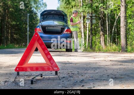 Panneau triangulaire d'avertissement portable sur le côté de la route rurale près d'une voiture Banque D'Images