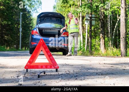 Panneau triangulaire d'avertissement portable sur le côté de la route rurale près d'une voiture Banque D'Images