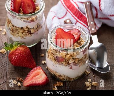 Parfait aux fraises, granola et yaourt dans un verre sur une table rustique en bois Banque D'Images