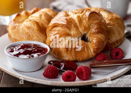 Gros plan de croissants avec conserves de framboises et framboises fraîches sur une assiette Banque D'Images