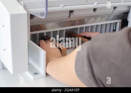 deux mains d'homme alignent une pile de cartes de visite ou d'étiquettes avec des pousseurs en bois dans une machine automatique de coupe de papier, un couteau professionnel, l'équipement pour Banque D'Images