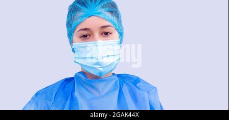 Épuisé personnel médical en uniforme bleu et dans un masque posé sur un appareil photo qui a l'air très fatigué. Banque D'Images