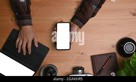 Un homme qui tient un téléphone portable et travaille avec une tablette d'ordinateur. Banque D'Images