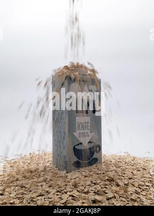 Un carton de lait d'avoine suédois 'Oatly' debout sur une base d'avoine crue avec de l'avoine versée sur le dessus du carton Banque D'Images