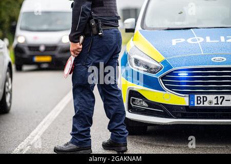 Emmerich, Allemagne. 31 juillet 2021. Un agent de police est muni d'un dispositif d'arrêt de police lors d'un contrôle d'entrée Corona effectué par la police fédérale à la frontière germano-néerlandaise et vérifie les véhicules dans la zone frontalière. Credit: Guido Kirchner/dpa/Alay Live News Banque D'Images