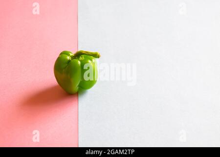 Un poivron vert sur l'arrière-plan des deux feuilles de cartes colorées avec mise au point sélective et espace de copie. Banque D'Images