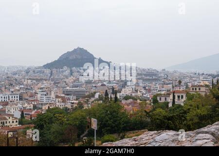 Vue sur le mont Lycabette et le centre de la vieille ville d'Athènes avec la verdure d'été en journée de brouillard gris depuis Areopagus - colline près de l'Acropole Banque D'Images