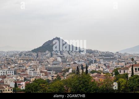 Vue sur le mont Lycabette et le vieux centre-ville d'Athènes avec des bâtiments à l'architecture en journée de brouillard gris d'Areopagus - colline près de l'Acropole Banque D'Images