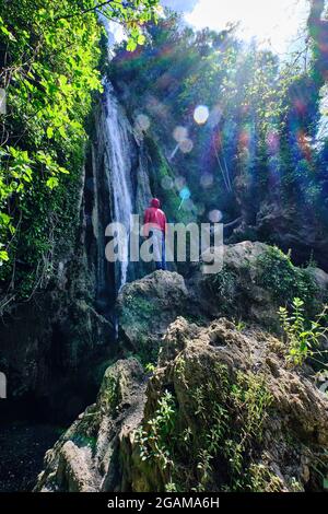 Jeune homme avec une cagoule rouge regardant les cascades de Chorrera de Balastar, Faraján. Coin unique de la province de Malaga en Andalousie Banque D'Images