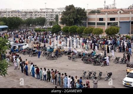 Un grand nombre de citoyens se réunissent dans une file d'attente pour administrer le vaccin anti Covid-19 sans aucune mesure de sécurité et de distance sociale qui peuvent causer la propagation du coronavirus (COVID- 19), montrant la négligence de l'autorité concernée, au centre d'exposition de Karachi le samedi 31 juillet 2021. Banque D'Images