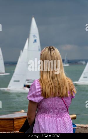 dame regardant la mer, dame regardant les bateaux à la semaine de cowes, femme spectateur à la régate de yachting, jeune femme se tenant à la mer, observant les yachts. Banque D'Images