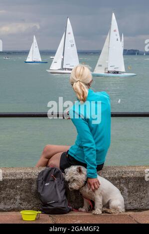 femme avec un petit chien regardant des courses de yacht à la régate annuelle de la semaine des cowes sur l'île de wight. Banque D'Images